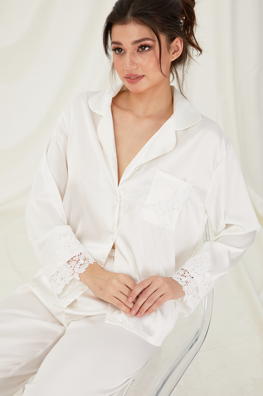 Woman wearing a white satin robe with lace trim on a plain background