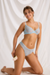 Model kneeling in baby blue polka dot bra and thong set with scalloped mesh edges