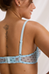 Back detail of baby blue polka dot mesh bra with adjustable shoulder straps, heart-shaped slider and hook fastening