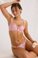 Pink cherry blossom embroidered bra and thong set shown in a seated pose with one arm raised
