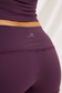 Back close-up of plum workout shorts, showing lace trim below the waistband and an M logo