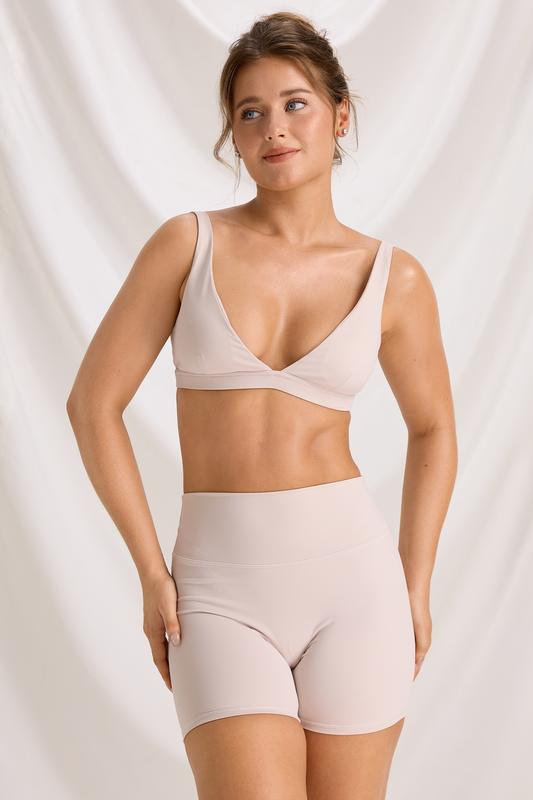 Model wearing the Bone High Waist Workout Set with a plunge sports bra and matching high-waisted shorts