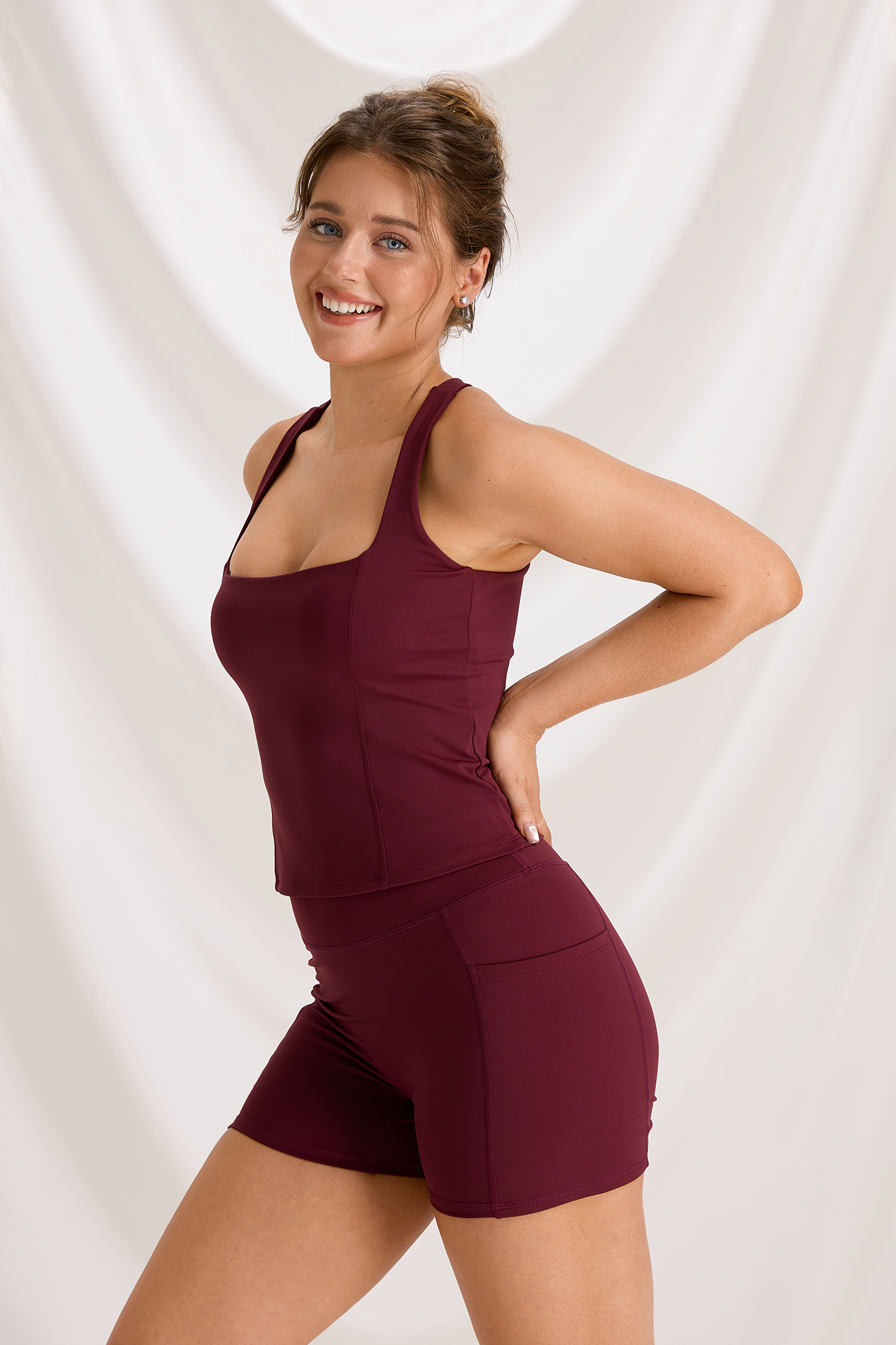 Three-quarter front view of the burgundy square-neck tank and matching workout shorts