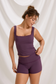Front view of a plum lace-trim workout tank and matching fitted shorts on a model