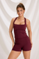 Front view of a model wearing a burgundy square-neck workout tank and matching high-waisted shorts