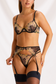 Black sheer lingerie set with yellow floral embroidery, an underwire bra, thong panty and garter belt, styled with stockings