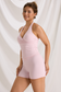 Three-quarter front view of a pink halter workout tank and matching high-waisted shorts on a model