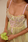 Close-up of embroidered yellow mesh lingerie with pink corset ribbon
